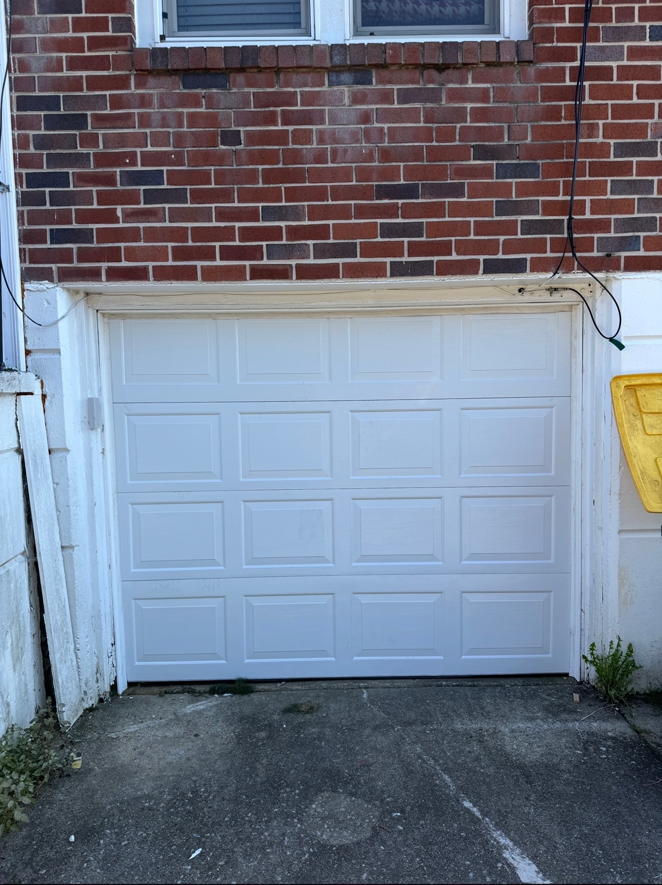 After: Brand new white garage door installed on the same brick townhouse